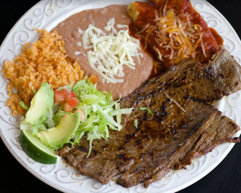 Carne asada plate with red enchiladas, rice, beans and salad